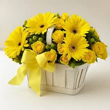 A basket filled with yellow roses and yellow gerberas