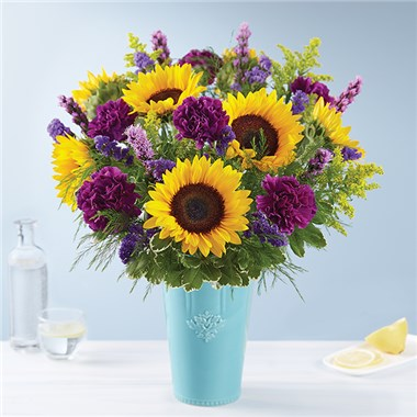 Golden sunflowers in a charming vase with purple carnations