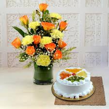 Lovely Yellow Carnations, Orange Roses in vase with fresh fruit Cake