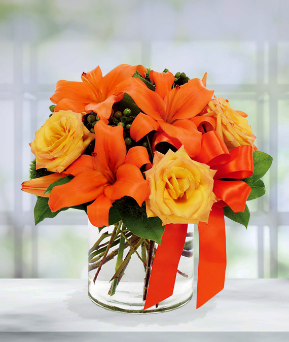 Orange Lilies and Yellow Roses merged in a glass vase.