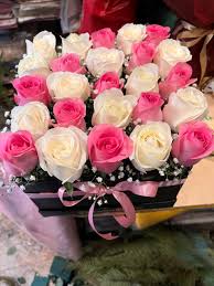 Pink and white roses displayed in a black box.