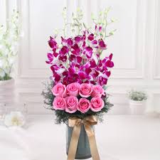 Pink roses with blue orchids in a vase.