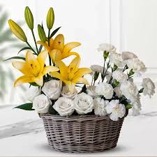 White carnations, white roses, and yellow lilies in a basket