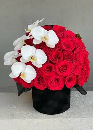 White orchids are paired with red roses in a black box.