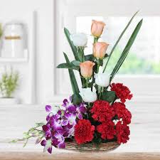 White roses, light pink roses merge with blue orchids and red carnations in a basket.